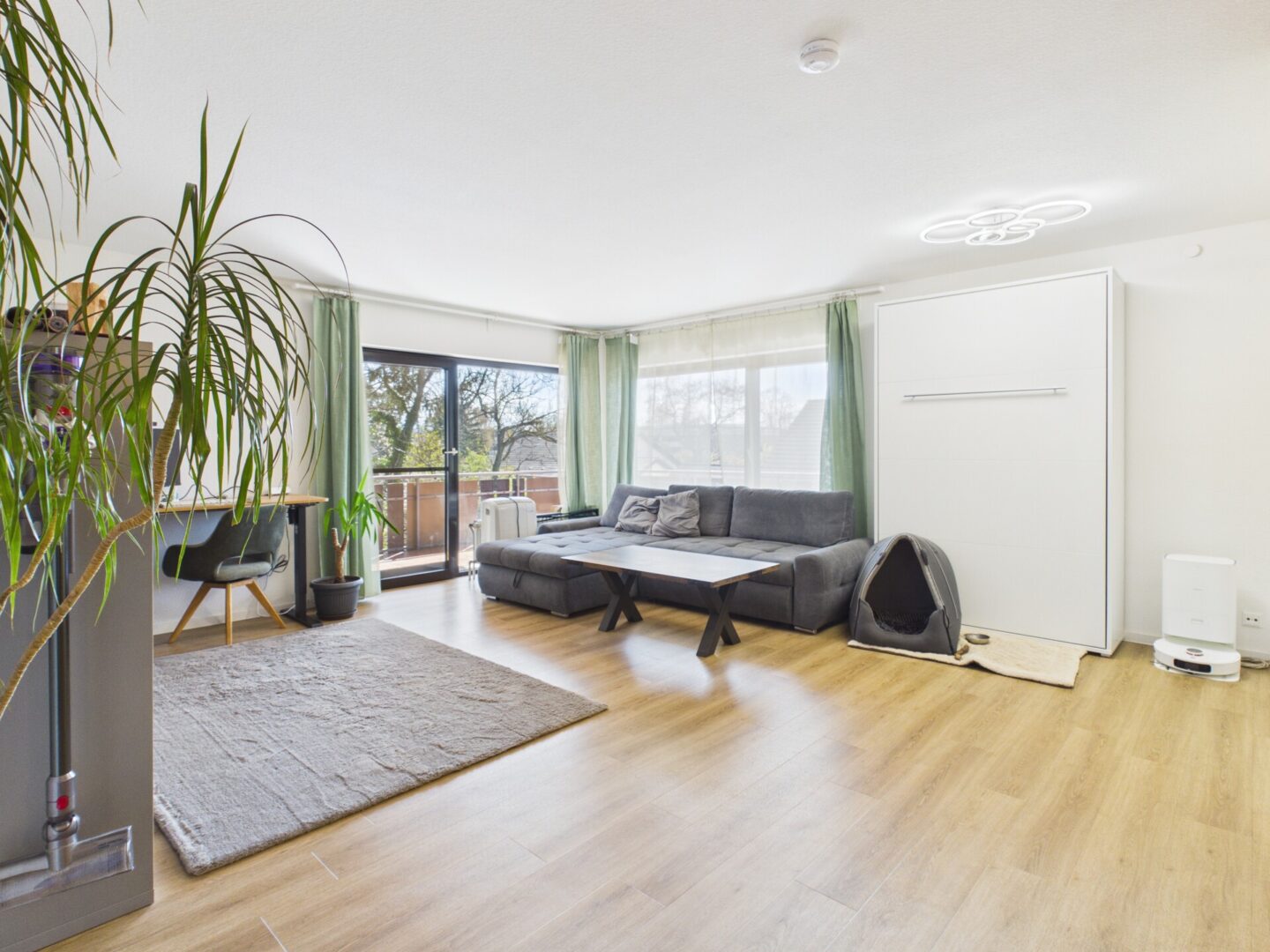 Helles Wohnzimmer mit bodentiefen Fenstern und Balkonzugang